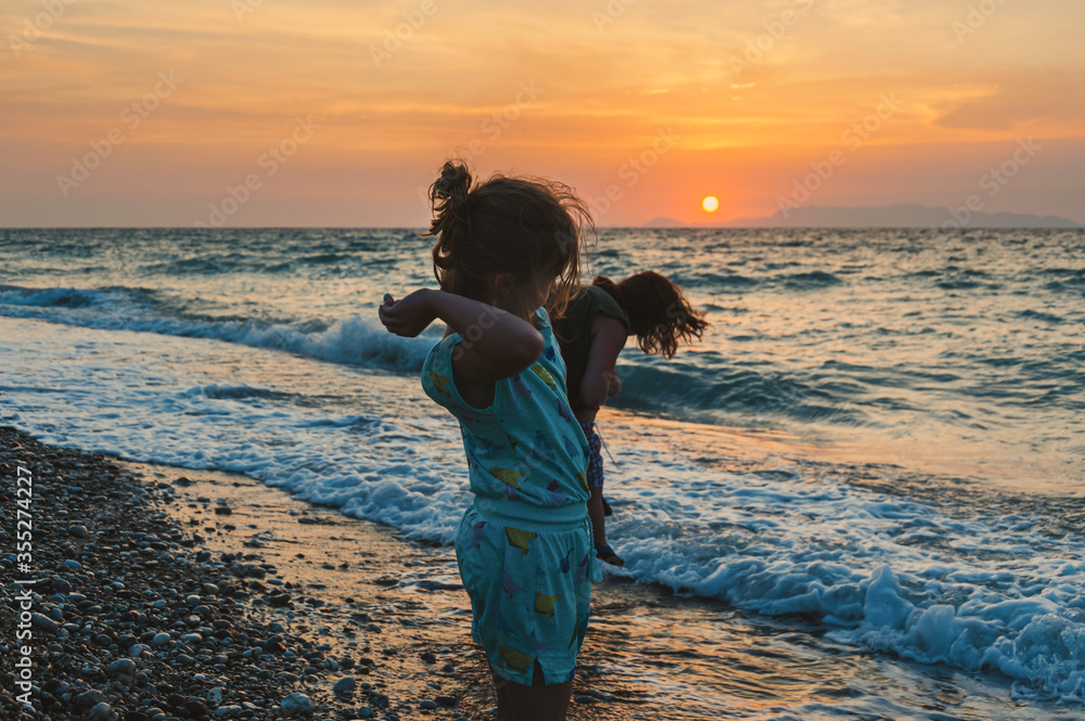 Family on pebble beach during sunset. West coast of Island of Rhodes. Greece.