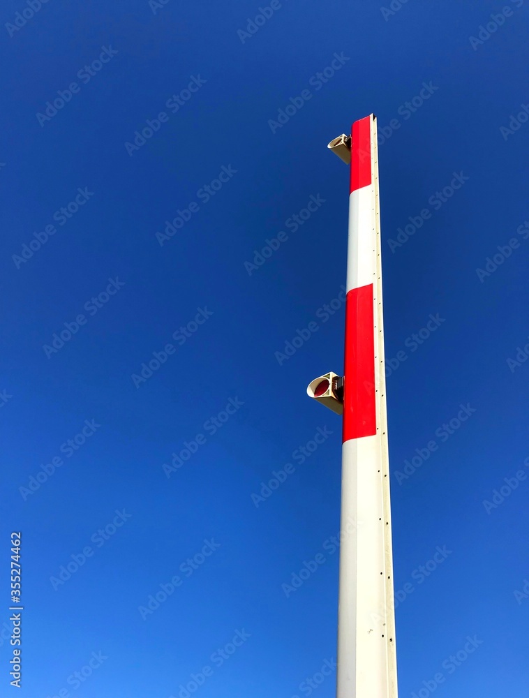 Arm of an automatic railway barrier in raised position against a deep blue sky. No people. Space for copy. Arm of an automatic railway barrier in raised position against a deep blue sky. No people. Space for copy.