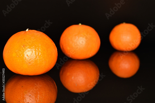 Bright yellow juicy, fresh, organic tangerines, close-up, on a black background.
