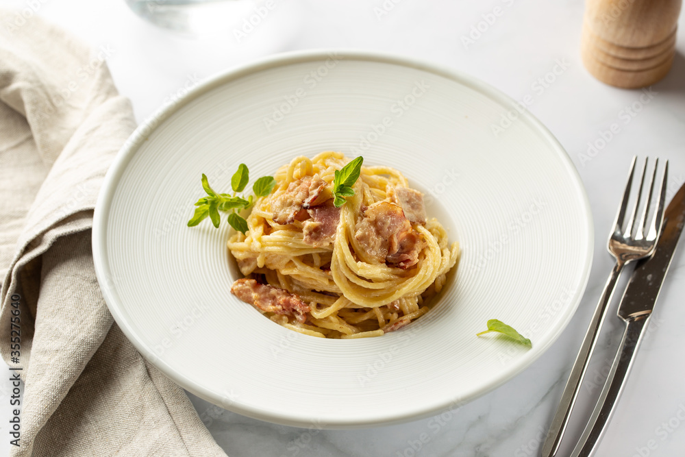 Pasta carbonara served in deep white plate with oregano