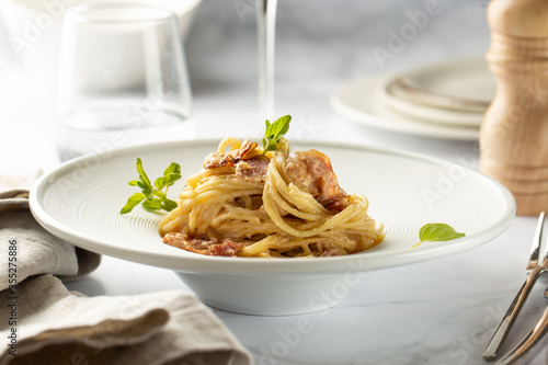 Pasta carbonara served in deep white plate with oregano