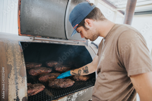 Man Checking Barbecue Meats in Smoker