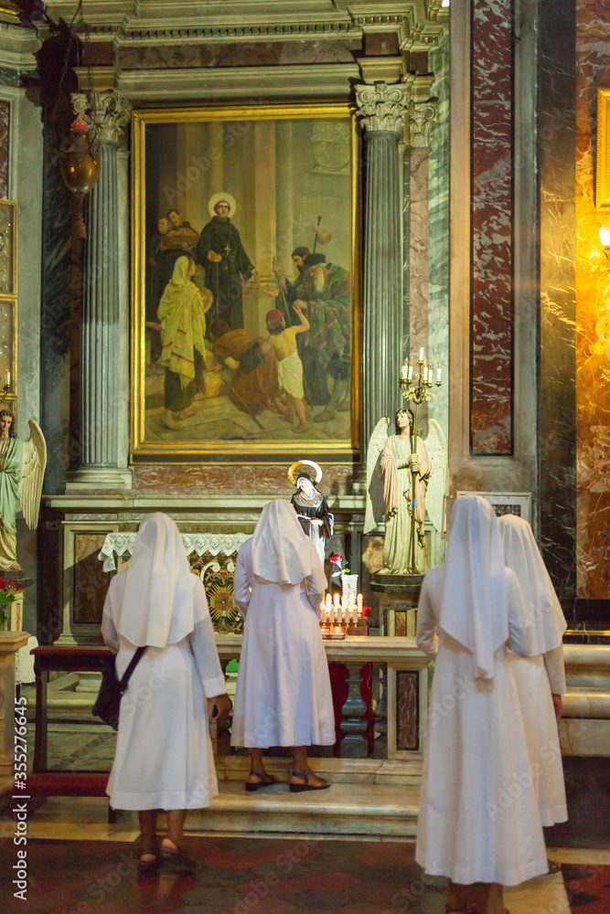 ROME, ITALY - 2014 AUGUST 17. Nuns lights a candle in the Church in Rome. ROME, ITALY - 2014 AUGUST 17. Nuns lights a candle in the Church in Rome.