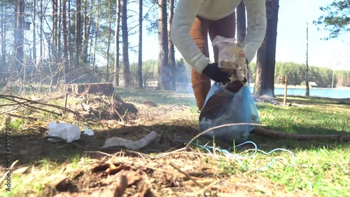 A girl collects garbage in the forest. Environmental pollution. A volunteer removes garbage. cleansing of the nature from plastic. photo