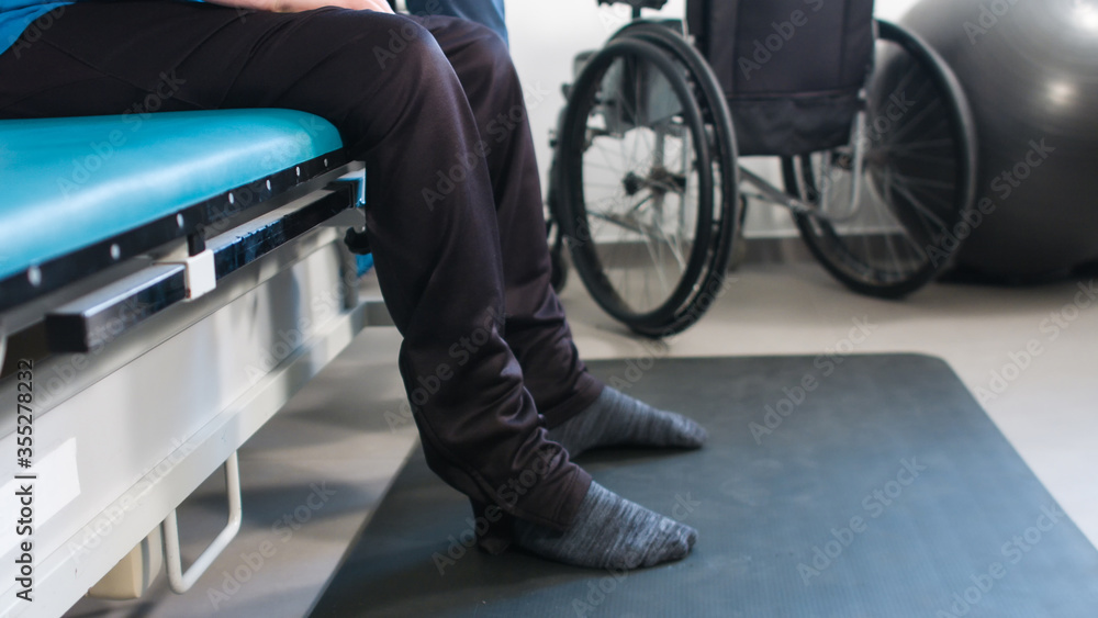 Physiotherapist exercising with disabled person using wheelchair on a therapy table. Physiotherapist exercising with disabled person using wheelchair on a therapy table.