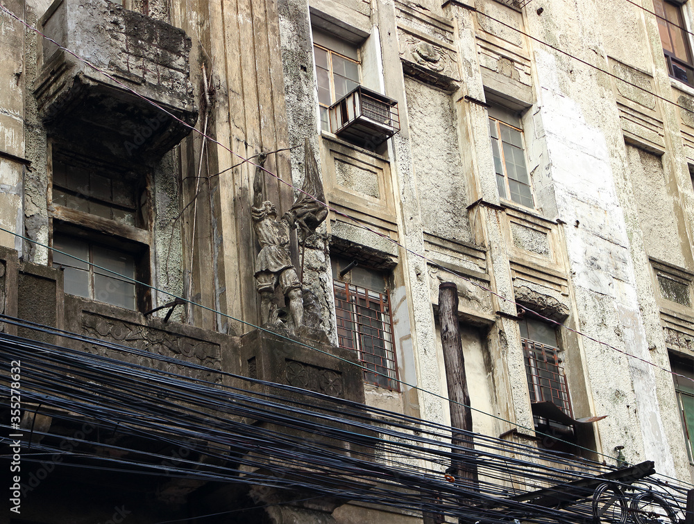 Facade of an old dilapidated building and numerous cables in Chinatown in Binondo district, Manila, Philippines