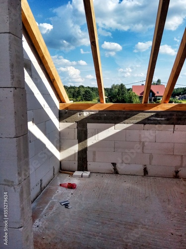 Attic under construction. house in basic state. Wooden roof construction, rafters, blocks and wreath. View of nearings through the roof.