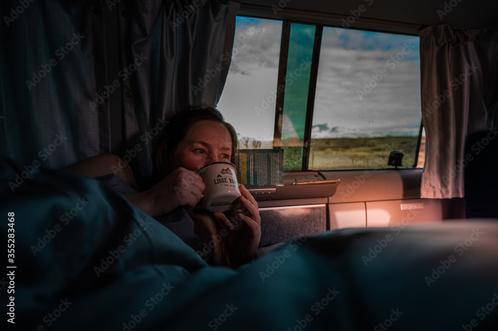 Woman enjoying coffee at the sunrise in the camper van on a roadtrip in Norway Woman enjoying coffee at the sunrise in the camper van on a roadtrip in Norway