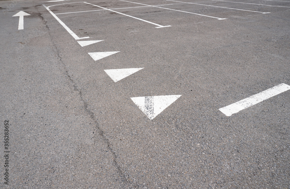 Dark asphalt road with marking lines. Tarmac texture. White disabled sign on a empty parking lot. Black tarmac texture with road marking 