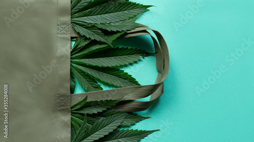 Hemp leaves in an eco bag on new mint color background. Responsible Consumption, zero waste. Flat lay, minimalist. Cannabis Hemp marijuana. photo