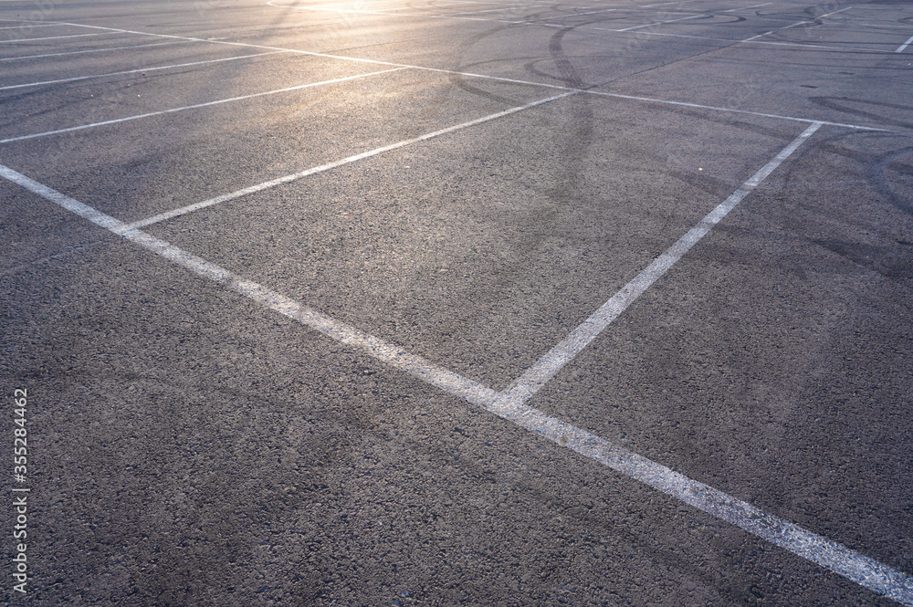 Dark asphalt road with marking lines. Tarmac texture. White disabled sign on a empty parking lot. Black tarmac texture with road marking 