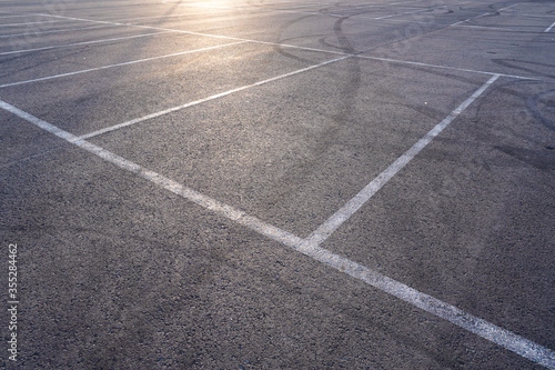 Dark asphalt road with marking lines. Tarmac texture. White disabled sign on a empty parking lot. Black tarmac texture with road marking 