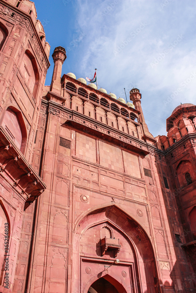 Looking up at the Red Stone Lahori Gate with Traditional Mughal Carvings with the Blue Sky and Clouds behind It at Delhi Red Fort in New Delhi, India 