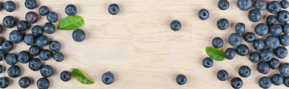 blueberry berries with green leaves on light wooden background top view blueberry berries with green leaves on light wooden background top view
