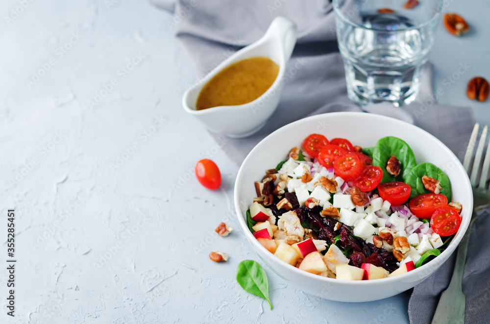 Chicken spinach apple tomato goat cheese salad in a bowl Chicken spinach apple tomato goat cheese salad in a bowl