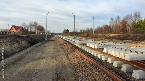 Railway works in small village. Railroad construction and modernisation site. Aerial view on excavator and railway track components.  photo