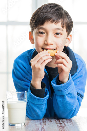 a child eating a cookie with a glass of milk
