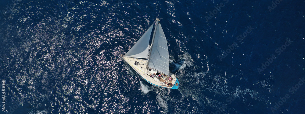 Aerial drone ultra wide photo of beautiful sail boat with white sails  sailing open ocean deep blue sea