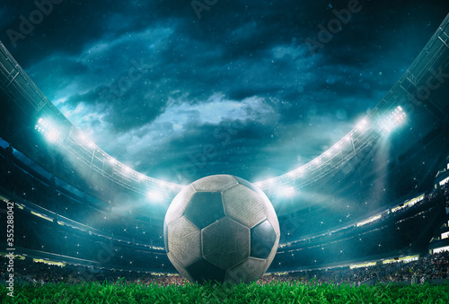 Close up of a soccer ball in the center of the stadium illuminated by the headlights © alphaspirit