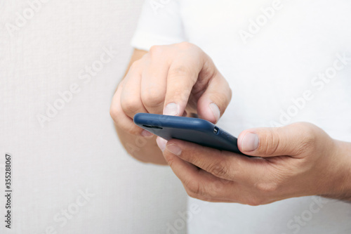 A person is holding a phone and tapping the screen on a white background with copy space. Concept of lifestyle business and Internet technologies in the office