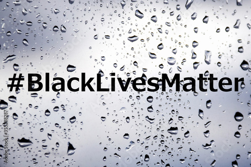 Raindrops on a transparent window of the house on a blurred background with the text Black Lives Matter. The concept of racism of black people, support and aggression