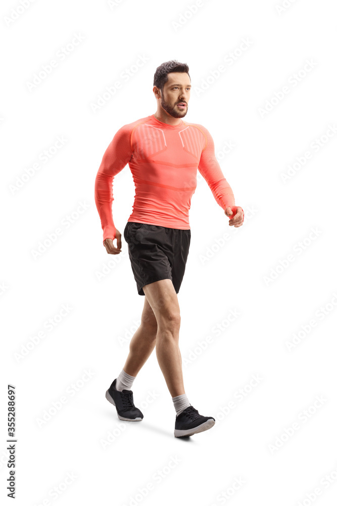 Good looking young man in sportswear walking fast