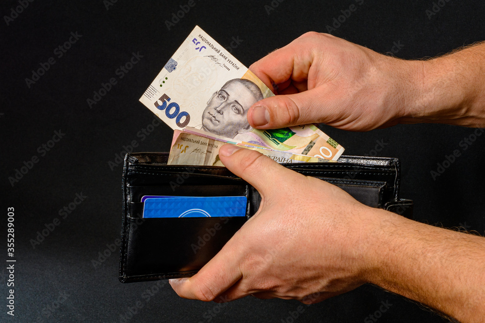 Ukrainian hryvnia in a black purse, a man holds in his hands. Ukrainian hryvnia in a black purse, a man holds in his hands.
