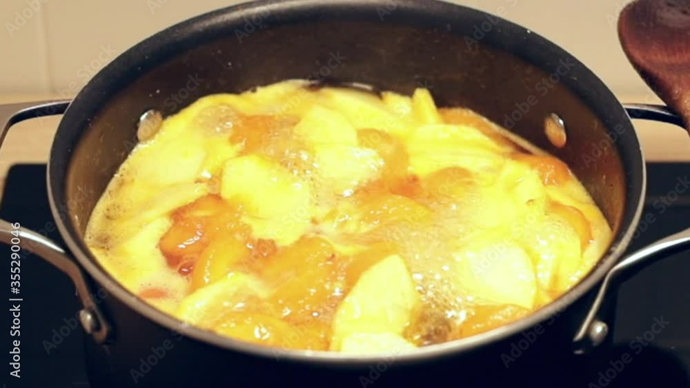 Homemade apricot jam, boling in a black pot. Preparing seasonal fruit preserve on induction stove. Homemade apricot jam, boling in a black pot. Preparing seasonal fruit preserve on induction stove.