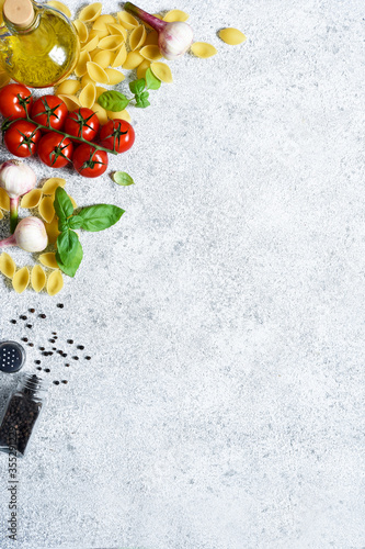 Raw pasta - Conchiglie with spices, tomatoes and basil on a concrete background. Top view. photo