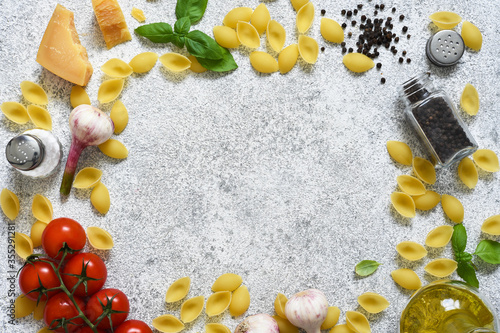 Food background with place for text. Raw pasta with spices, tomato and basil on a concrete background. Top view. photo