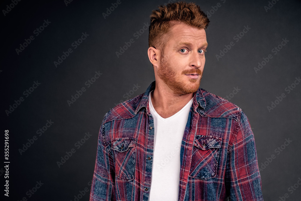 Headshot of intrigued good-looking ginger male with bristle in blue shirt turning at camera with impressed and curious expression, listening to interesting story carefully over gray background Headshot of intrigued good-looking ginger male with bristle in blue shirt turning at camera with impressed and curious expression, listening to interesting story carefully over gray background
