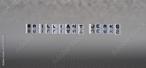 Фотография brilliant jerks concept represented by black and white letter cubes on a grey ho