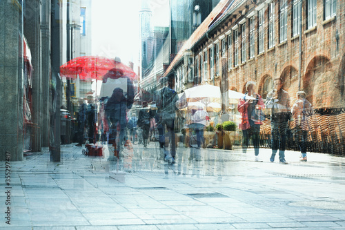 Abstract city life, people are walking and shopping in the pedestrian zone in the old town, multiple exposure and motion blur, copy space photo