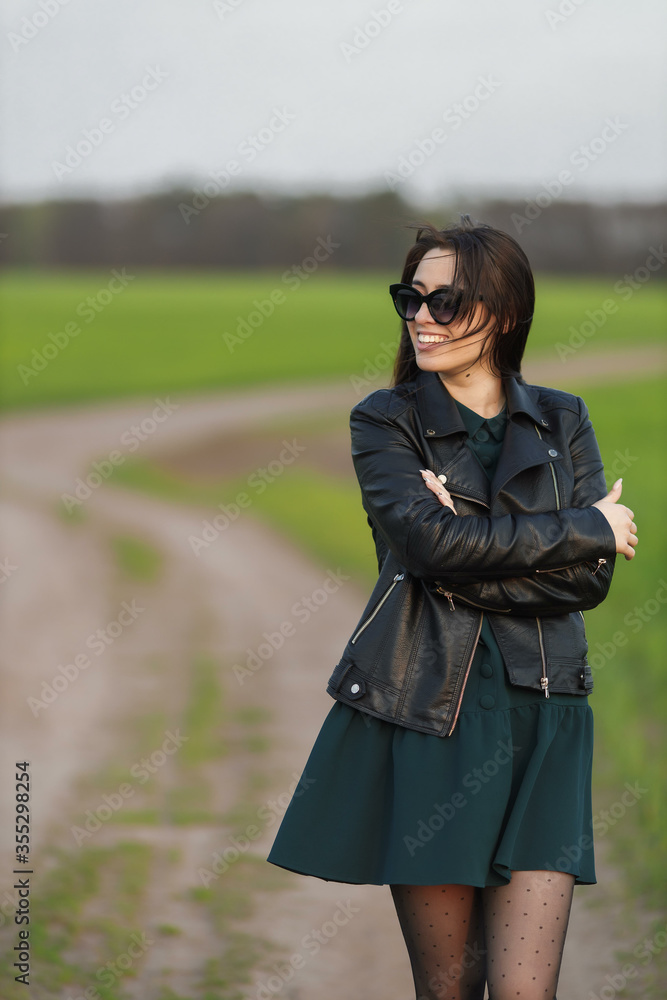 Full length portrait of a stylish girl walking along a green field. A young smiling woman is walking in nature. Green spring meadow Full length portrait of a stylish girl walking along a green field. A young smiling woman is walking in nature. Green spring meadow