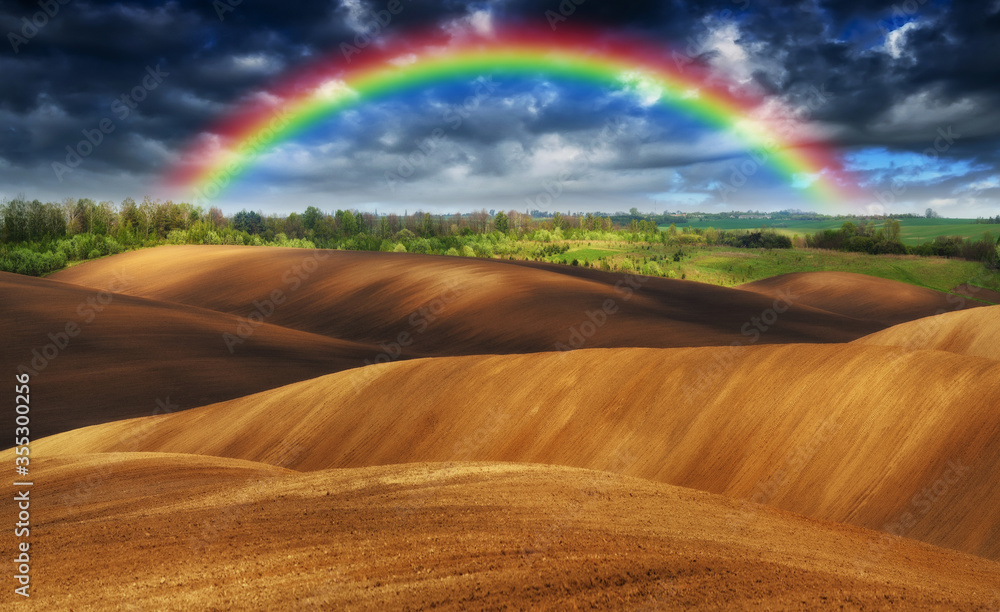 Rainbow over a picturesque hilly field Rainbow over a picturesque hilly field