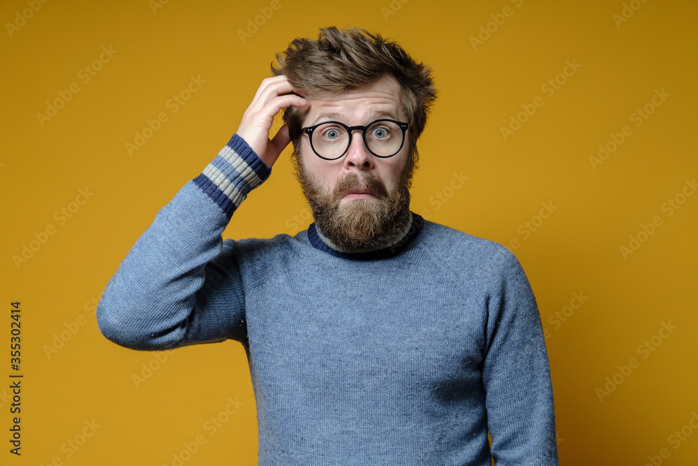 Funny, puzzled man tries to remember something, gathers thoughts, clings to his head with hand and looks bewildered. Funny, puzzled man tries to remember something, gathers thoughts, clings to his head with hand and looks bewildered.