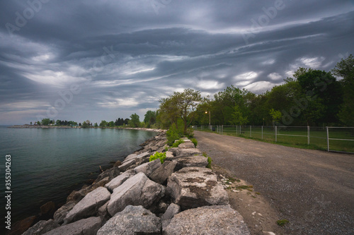 Fototapeta Naklejka Na Ścianę i Meble -  lake and clouds with waterfront trail during dramatic weather 