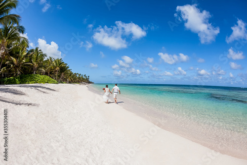 Tela Newlyweds holding hands hugging at white sandy tropical caribbean beach landscap
