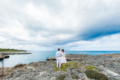 Fotografie Newlyweds holding hands hugging at white sandy tropical caribbean beach landscap
