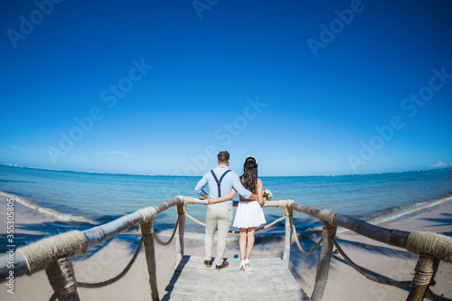 Photographie Newlyweds holding hands hugging at white sandy tropical caribbean beach landscap