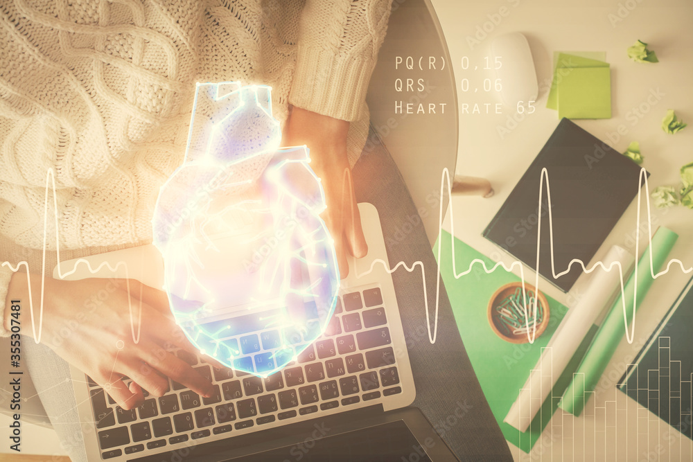 Double exposure of woman hands working on computer and heart hologram drawing. Top View. Medical Science concept. Double exposure of woman hands working on computer and heart hologram drawing. Top View. Medical Science concept.