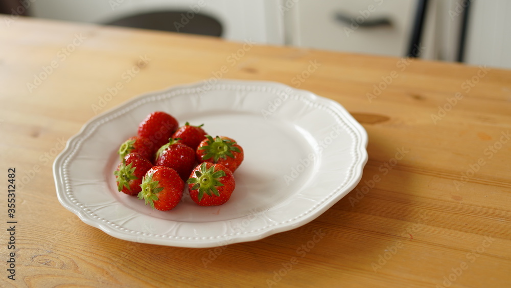 Close up of ripe strawberries on plate on table in kitchen. Close up of ripe strawberries on plate on table in kitchen.