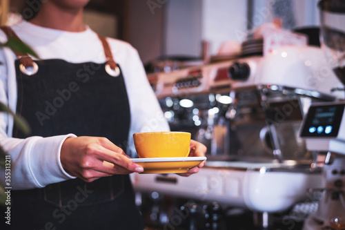 Coffee Business Concept.Asian woman wear blue apron holding hot coffee cup Submit to the customer