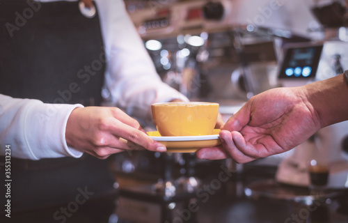 Coffee Business Concept.Asian woman wear blue apron holding hot coffee cup Submit to the customer © PK Studio