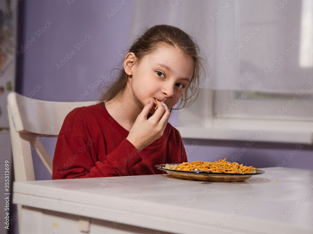 Pretty grimacing kid girl eating tasty spaghetti on the dinner on the home kitchen table. Closeup Pretty grimacing kid girl eating tasty spaghetti on the dinner on the home kitchen table. Closeup
