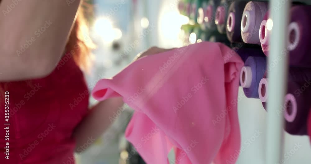 Close tailor hands chooses the right shade of thread for sewing of set of spools Close tailor hands chooses the right shade of thread for sewing of set of spools