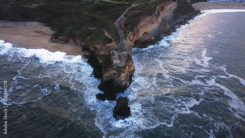 An iconic place on the Atlantic coast, the Mecca of big-wave surfing. View of Nazare's lighthouse in Zon North Canyon, place with the biggest waves in Europe, Nazare, Portugal An iconic place on the Atlantic coast, the Mecca of big-wave surfing. View of Nazare's lighthouse in Zon North Canyon, place with the biggest waves in Europe, Nazare, Portugal