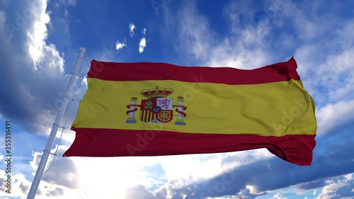 Realistic Flag of Spain waving at wind in slow with blue sky photo