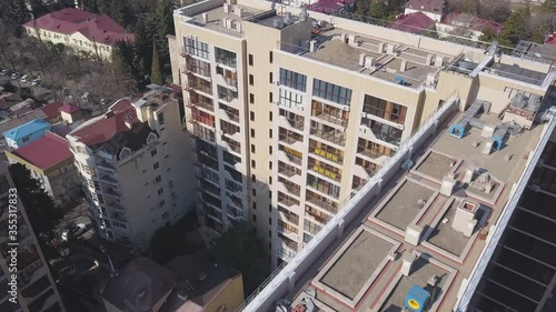 Aerial view of high rise residential building. Clip. Flying above the apartment house in the sleeping area of the city with parked cars on a summer sunny day. photo