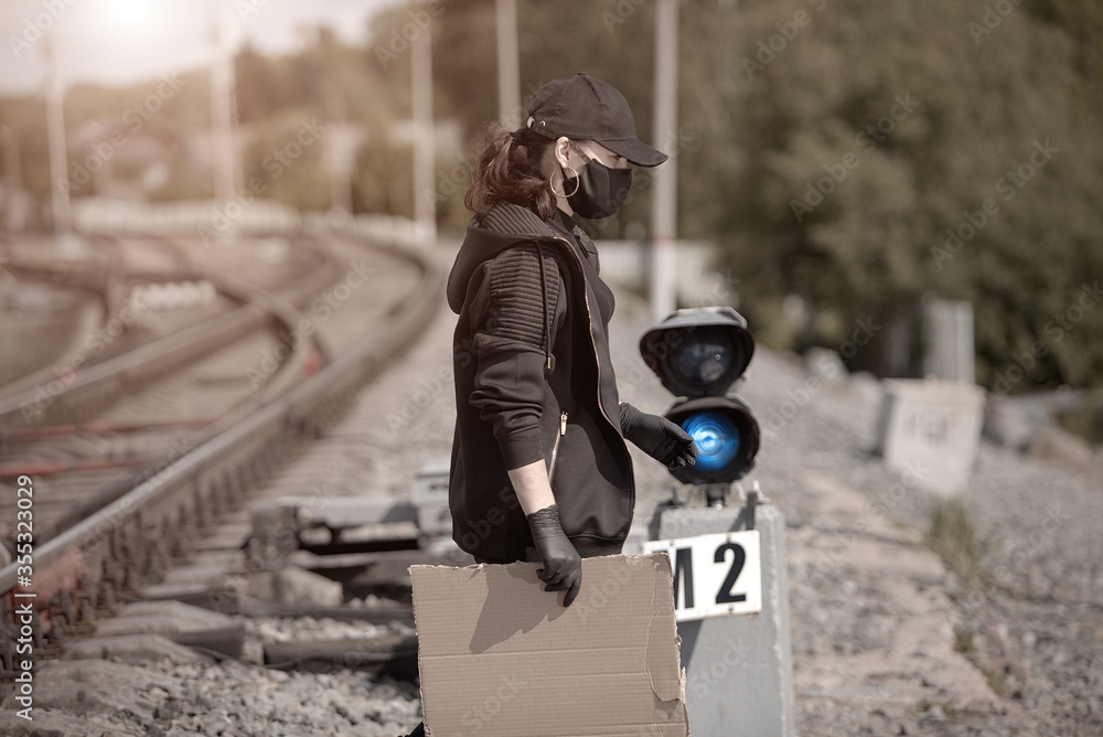 a young activist with a poster in her hand at a railway station, dressed in black clothes a young activist with a poster in her hand at a railway station, dressed in black clothes